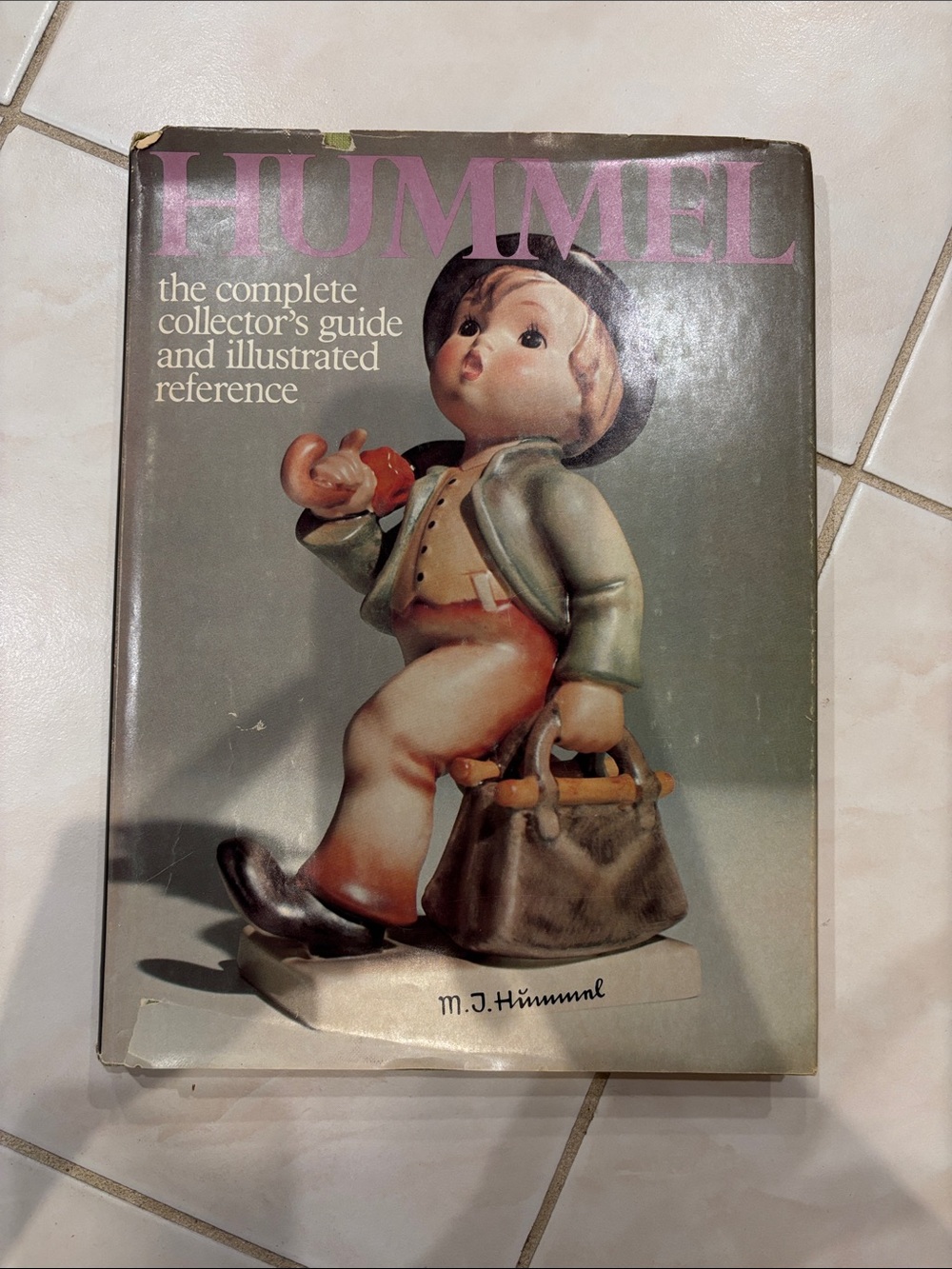 Hummel Book Cover Featuring Figurine in Green Jacket and Pink Logo